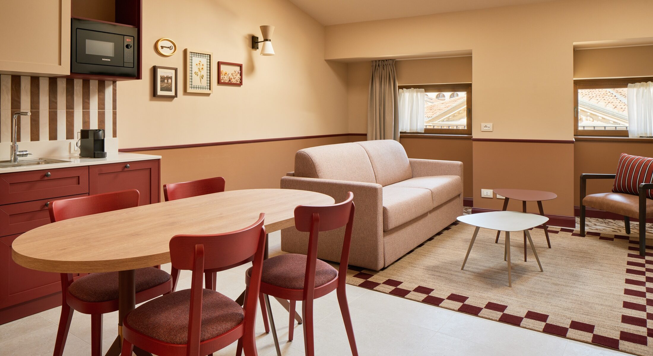 Soggiorno mansardato con cucina, tavolo rotondo e sedie rosse – Homy Livia Verona