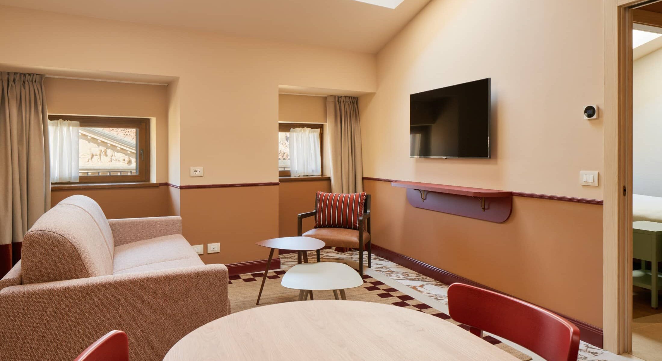 Zona giorno mansardata con divano e TV a parete – Homy Livia Verona