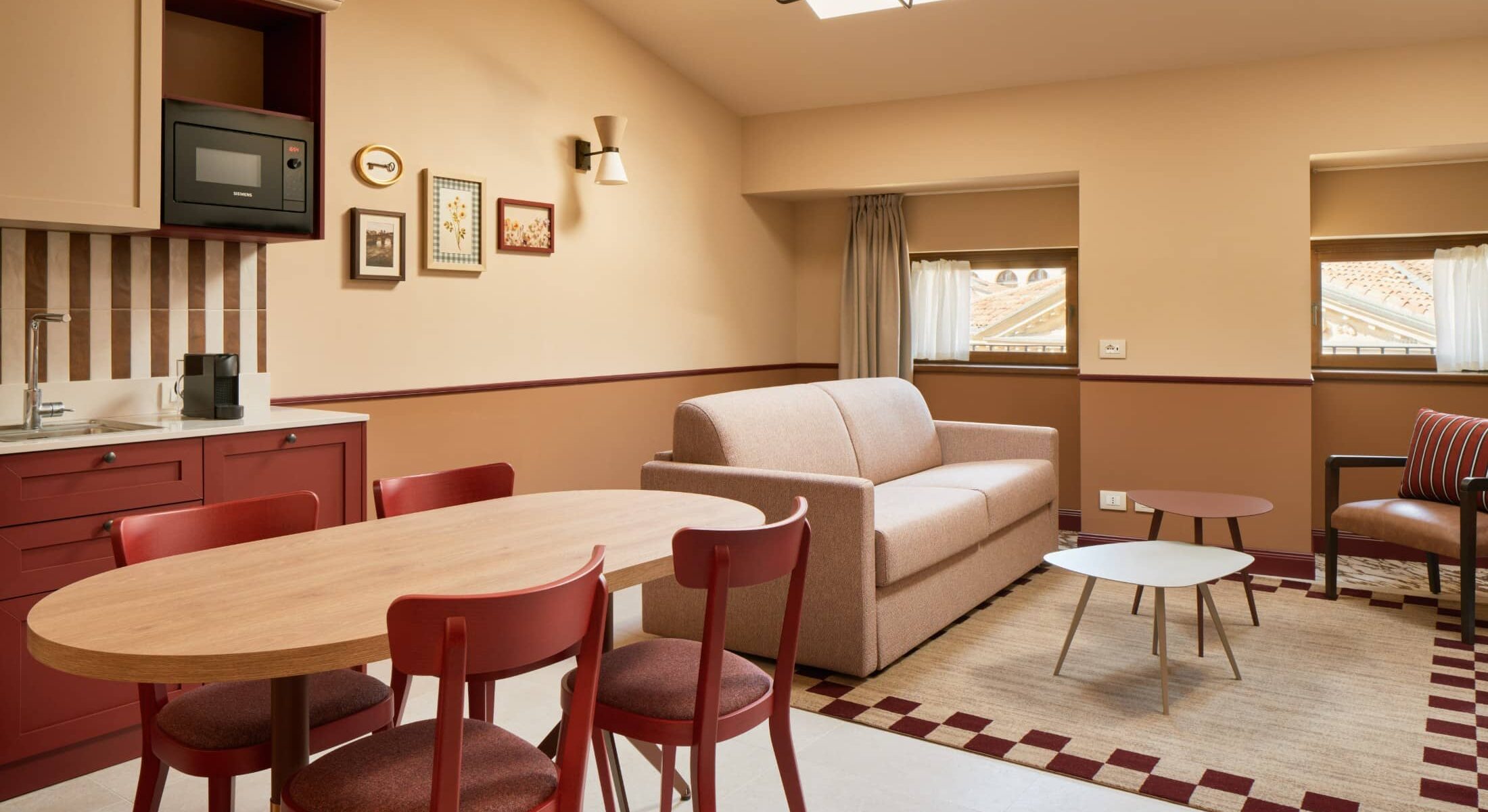 Soggiorno mansardato con cucina, tavolo rotondo e sedie rosse – Homy Livia Verona