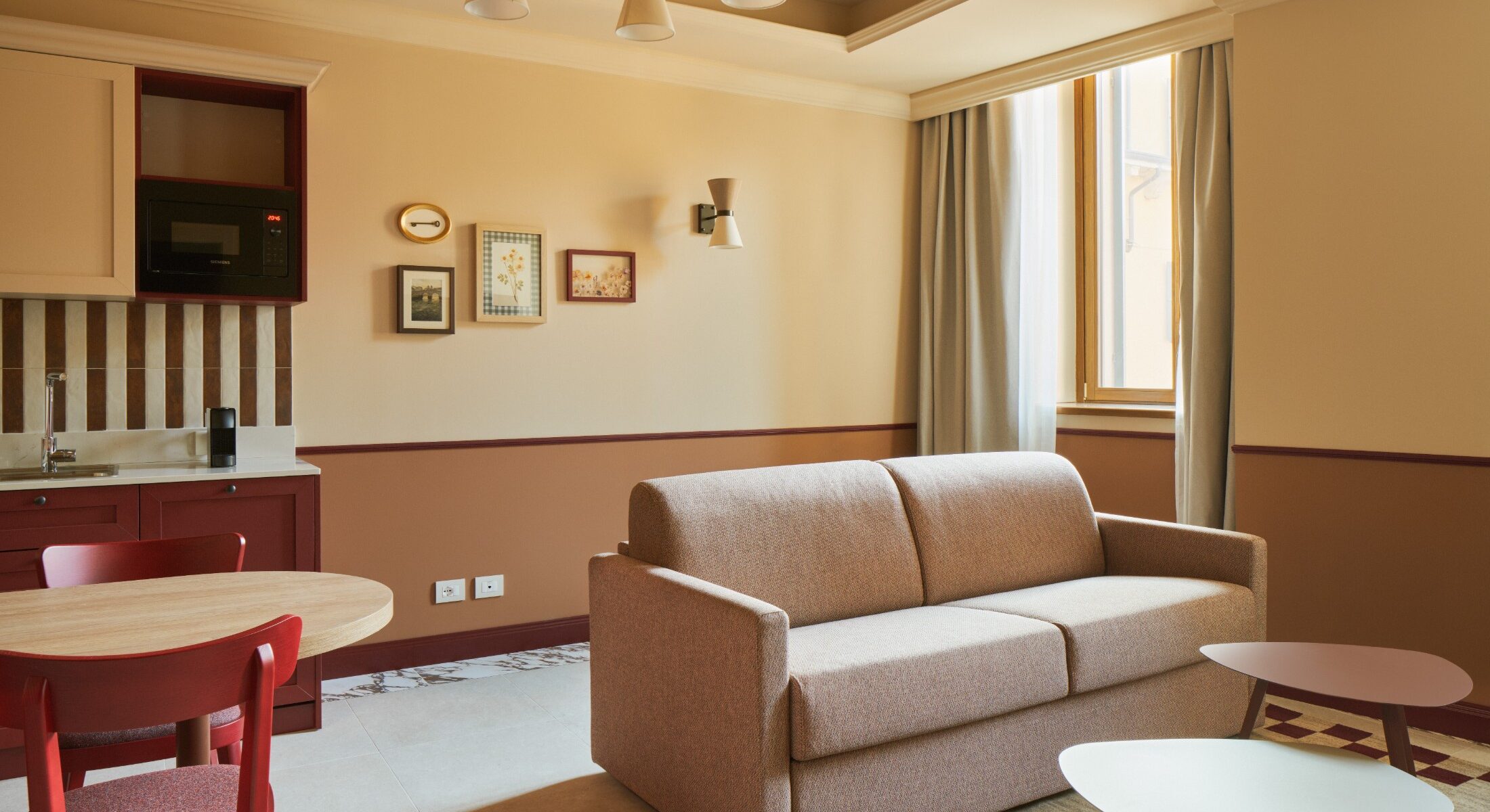 Zona giorno con divano beige e pavimento con tappeto decorato – Homy Livia Verona