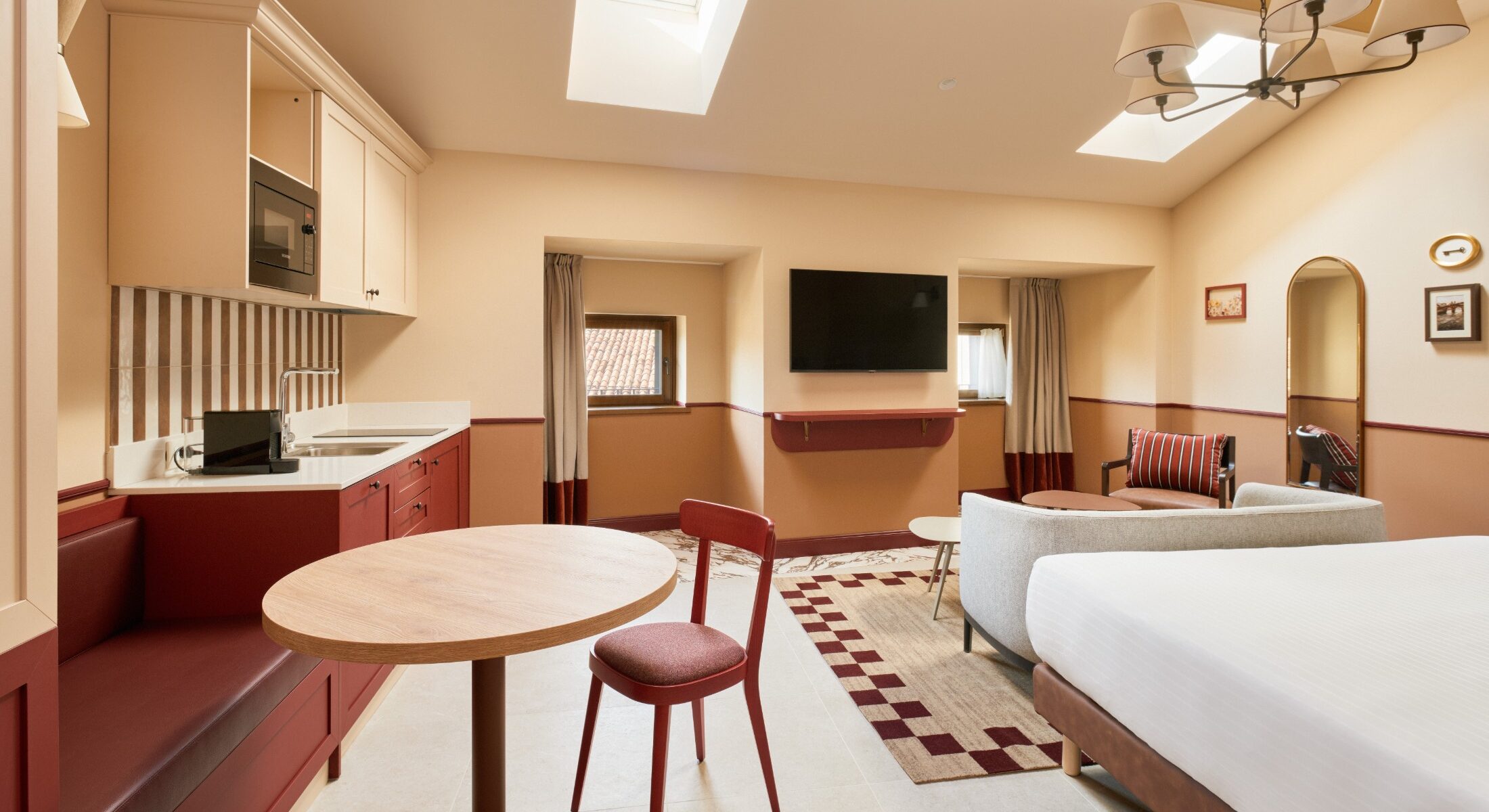 Camera luminosa con letto, cucina e tavolino rotondo in legno – Homy Livia Verona