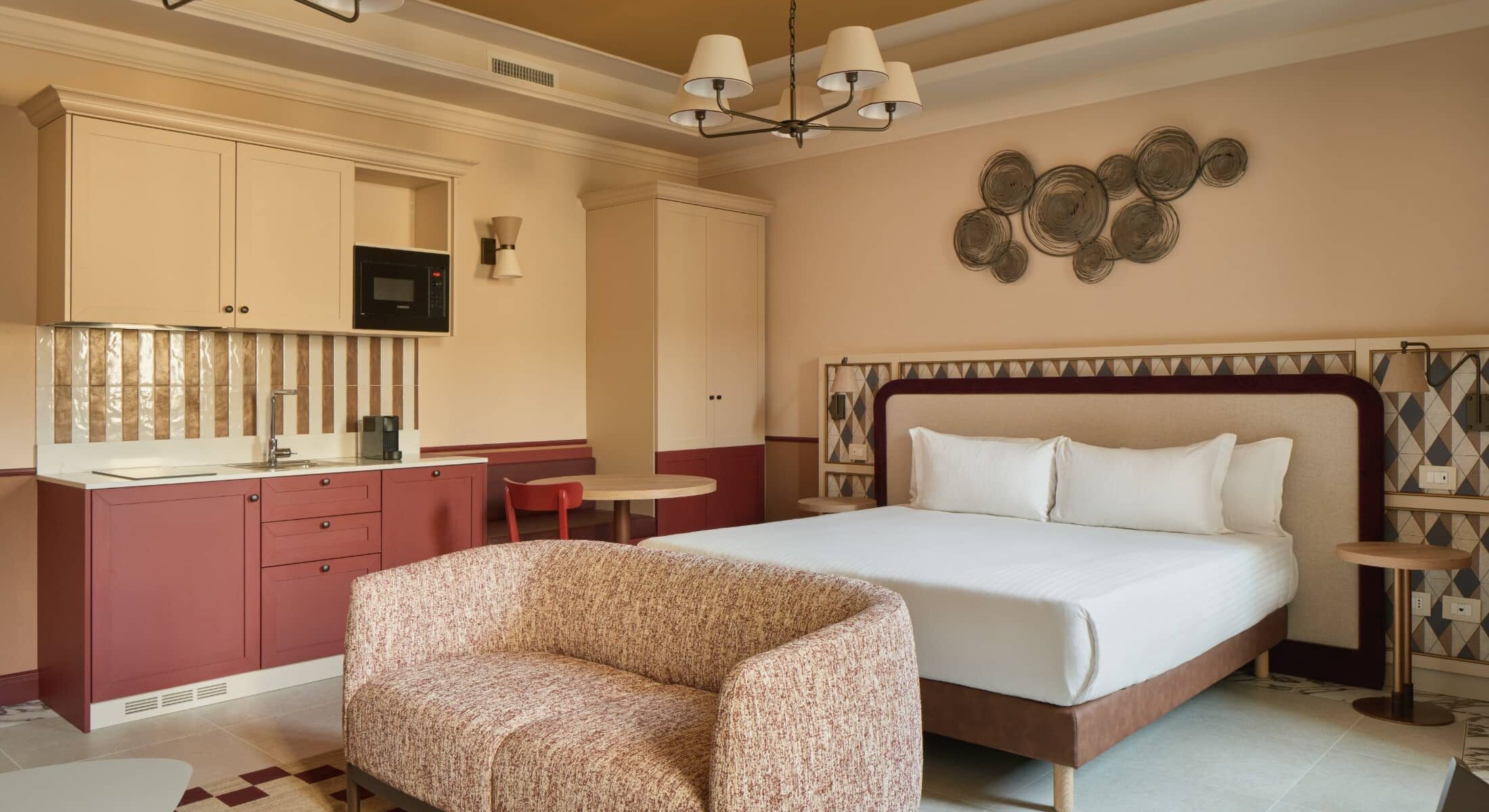 Zona giorno con letto, divano, cucina e tavolino bianco – Homy Livia Verona