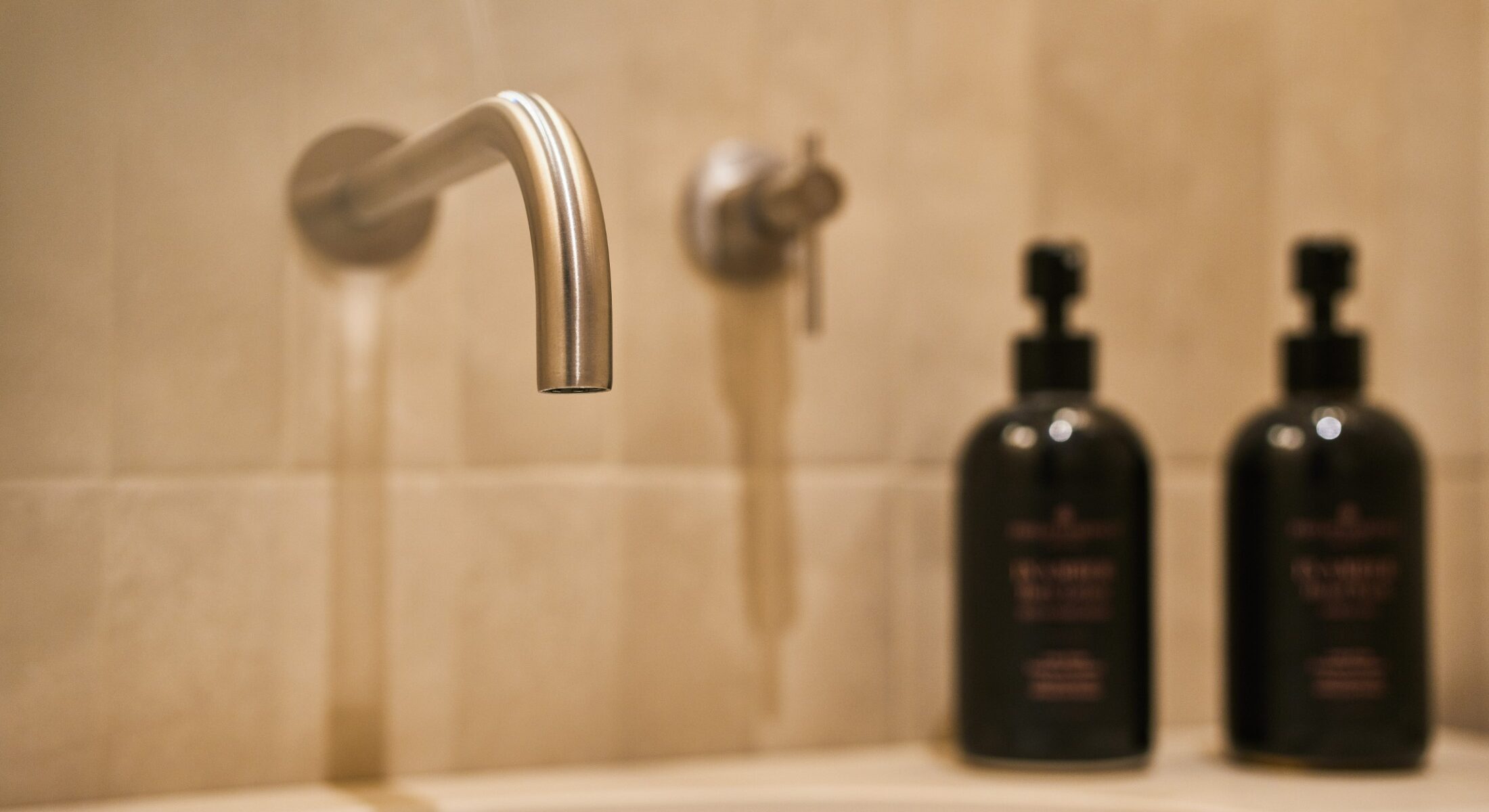 Dettaglio di rubinetto e flacone nero su lavabo in marmo – Homy Livia Verona