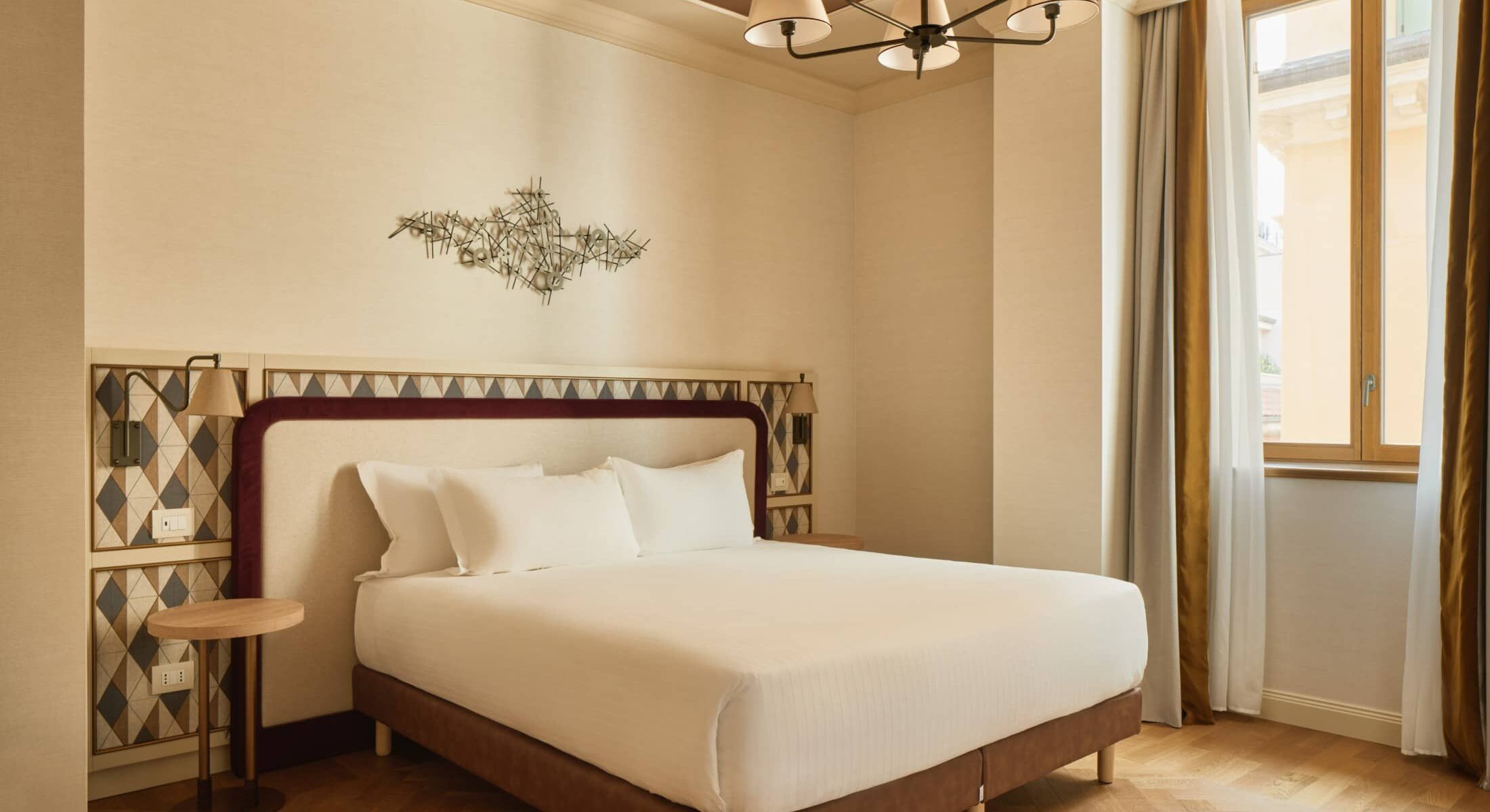 Camera matrimoniale luminosa con letto e tende beige – Homy Livia Verona