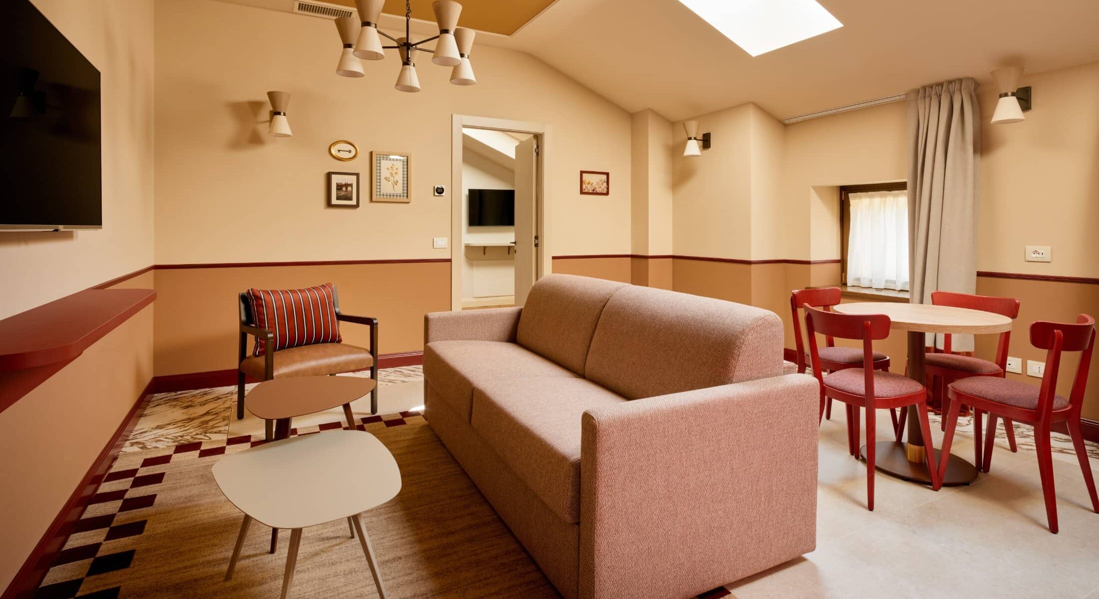 Zona living mansardata con divano rosso e tavolo rotondo – Homy Livia Verona